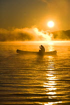 Canoeing in Lily Bay iin the mist at sunrise, Moosehead Lake, Maine, USA.  model released