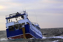 Fishing vessel "Ocean Harvest" shooting her net over the stern. North Sea, December 2008.  Property Released.