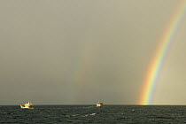 Rainbow over sea with fishing boats and dark rain clouds, Yasawa Islands, Fiji.
