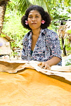 Young woman shows how local tapa (bark) cloth is dyed and prepared. Village tour and dance performance at Nembao Village, Utupua Island, Solomon Islands May 2008