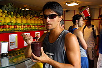 Man eating acai palm fruit juice at store, Ipanema, Rio de Janeiro, Brazil.