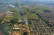 Aerial view of Ariquemes town, with smoke rising from the ovens that make charcoal out of wood from the Amazon Rainforest, Rondônia State, Western Brazil.