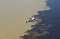 Aerial view of cargo boat at the Meeting of the waters of Negro and Soilimões rivers that form the Amazonas River, 14km west of Manaus, in Amazonas State, Northern Brazil.