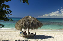Tropical beach with tourists under straw umbrella,  Catalina Island, Dominican Republic.