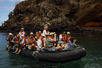 Group of tourists in inflatable boat beside the shore of Punta Cormorant, Floreana (Charles) Island, Galapagos Islands, Ecuador, Nov 2007.