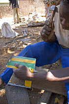 Gambian man hammering scrap metal reclaimed from traditional taxi, The Gambia, 2008