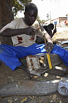 Gambian man hammering scrap metal, making a stove, The Gambia, 2008