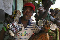 Artisan holding up toy cars and a bike crafted from discarded cans, The Gambia, 2008