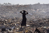 Gambian girl stretching between sifting for recyclable material, Mannjai Kunda rubbish dump, The Gambia, 2008