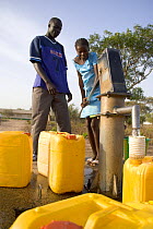 Gambians using hand pump to fill water barrels, Lamin, The Gambia, 2008
