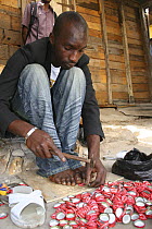 Artisan hammering holes into coke bottle tops, Dakar, Senegal, 2008