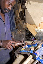 Craftsman making ashtray from discarded drinks cans, Dakar, Senegal, 2008