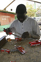 Artisan soldering toy cars, crafted from discarded cans, Dakar, Senegal, 2008