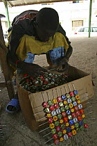 Artisan putting old bottle tops onto wire, Dakar, Senegal, 2008