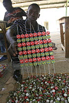 Artisan with grid of recycled bottle tops threaded on wire, Dakar, Senegal, 2008