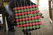 Artisan with grid of recycled bottle tops threaded on wire, Dakar, Senegal, 2008