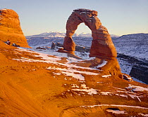 Delicate Arch and La Sal Mountains in the distance, with light snow dovering, Arches National Park, Utah, USA.