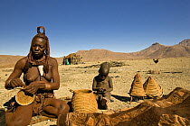 Himba woman making baskets, with child sitting nearby, Skeleton Coast, Namibia, Model released