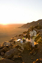 Guide preparing evening drinks for tourists as they watch the sunset, Sossusvlei, Namib-Naukluft National Park, Namibia