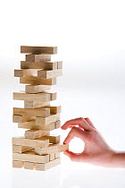 Why biodiversity matters. Person pulling wooden block from game of Jenga, all blocks above will come tumbling down, Scotland, UK, 2007
