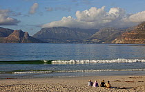 Four people sitting on beach, South Africa. December 2008.