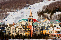 Colourful village of Mount Tremblant with busy ski slopes in background. Quebec, Canada, 2008.