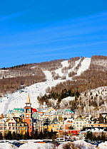 Colourful village of Mount Tremblant with busy ski slopes beyond. Quebec, Canada, 2008.