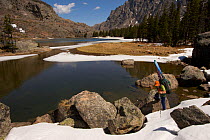 Skier Phil Atkinson passing Elk Lake on the East Rosebud Creek Trail into the Beartooth Mountains, Montana, USA May 2008