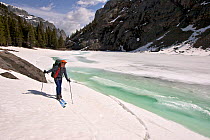 Skier Phil Atkinson skiing past Rimrock Lake, Beartooth Mountains, Montana, USA May 2008