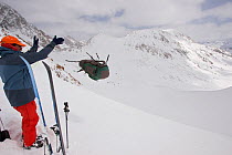 Skier Phil Atkinson tosses his pack from an 11,500 ft pass near Granite Peak, Beartooth Mountains, Montana, USA. May 2008