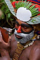 Villager applies face paint at Payakona Village singsing ceremony. Mount Hagen vicinity in the Western Highlands Province, Papua New Guinea. September 2004