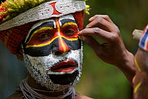 Man applying face paint at Payakona Village singsing ceremony. Mount Hagen vicinity in the Western Highlands Province, Papua New Guinea. September 2004