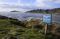 "Dangerous Cliffs: No Access to Beach" warning sign, with Burgh Island in the distance. Bantham Bay, South Devon, UK. January 2009.