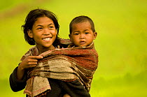 Girl carrying child on her back in the rice fields, central Madagascar.