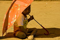 Child sitting under umbrella at a party to celebrate the 5th of June, World Environment Day, Manerinerina, Majunga, Madagascar.