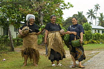 Women walking home in the rain wearing the local Pandanus mat skirts, Tonga, Melanesia, 2007