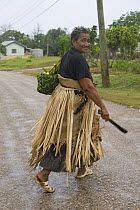 Woman walking home in the rain wearing the local Pandanus mat skirt, Tonga, Melanesia, 2007