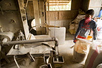Milling / husking the harvested threshed rice. The husk is striped from the rice by passing the rice through two spinning rubber roles, one roll spinning faster than the other. Camarines Sur, Luzon, P...