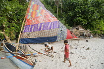 Fisherman preparing his fishing gear and boat to go night fishing with his son, Camarines Sur, Luzon, Philippines 2008.