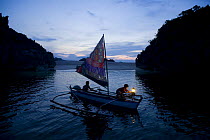 Fisherman and son on traditional sailboat out for night fishing using a kerosine "Petromax" lamp to attract fish, Camarines Sur, Luzon, Philippines 2008.