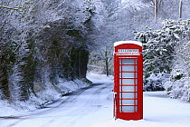 Red telephone box in snow covered country lane, Wiltshire, UK, winter 2008/9