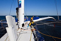 Crew member running over trampoline aboard Maxi yacht "Banque Populaire V", skippered by Pascal Bidegorry, practicing off Cadiz, Spain. March 2009.