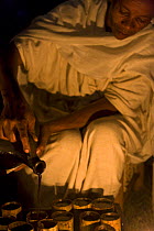 Ethiopian woman pouring coffee (Coffea arabica) from traditional terracotta pitcher into bamboo cups, Bonga, Kaffa Zone, Southern Ethiopia, East Africa December 2008