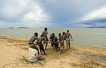 Young men and boys hauling in fishing boat half a kilometre out at Lake Malawi, Chipoka, Malawi. February 2008
