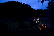 Fisherman beside camp fire at night, River Orkla, Norway, September 2008 (Model released)