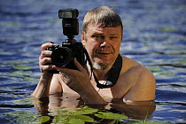 Photographer Lassi Rautiainen holding camera in water, Kuhmo, Finland, July 2008