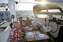 Friends eating a meal aboard Amel 54 ketch "Hollis" on delivery from Martinique, Caribbean.  Model and property released.