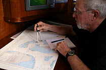 Man navigating with paper charts aboard Amel 54 ketch "Hollis" on delivery from Martinique, Caribbean. 2006.  Model and property released.