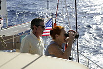 Couple looking out to sea with binoculars, aboard Amel 54 ketch "Hollis" on delivery from Martinique, Caribbean. 2006.  Model and property released.