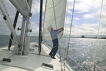 Man setting the sails on the foredeck of a 53ft Stephens yacht, Florida.  Model and property released.